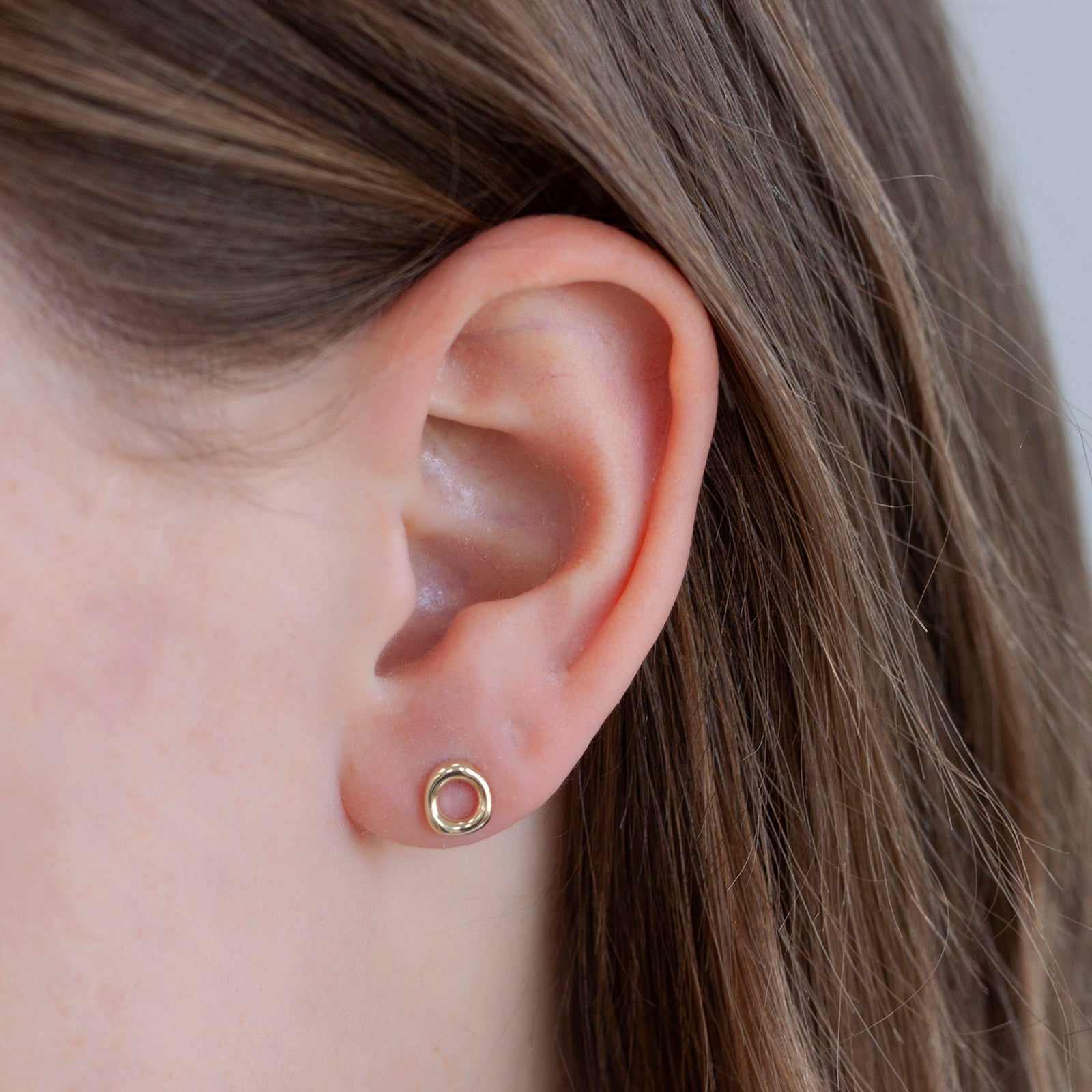 9 ct gold halo stud earring in a models ear 