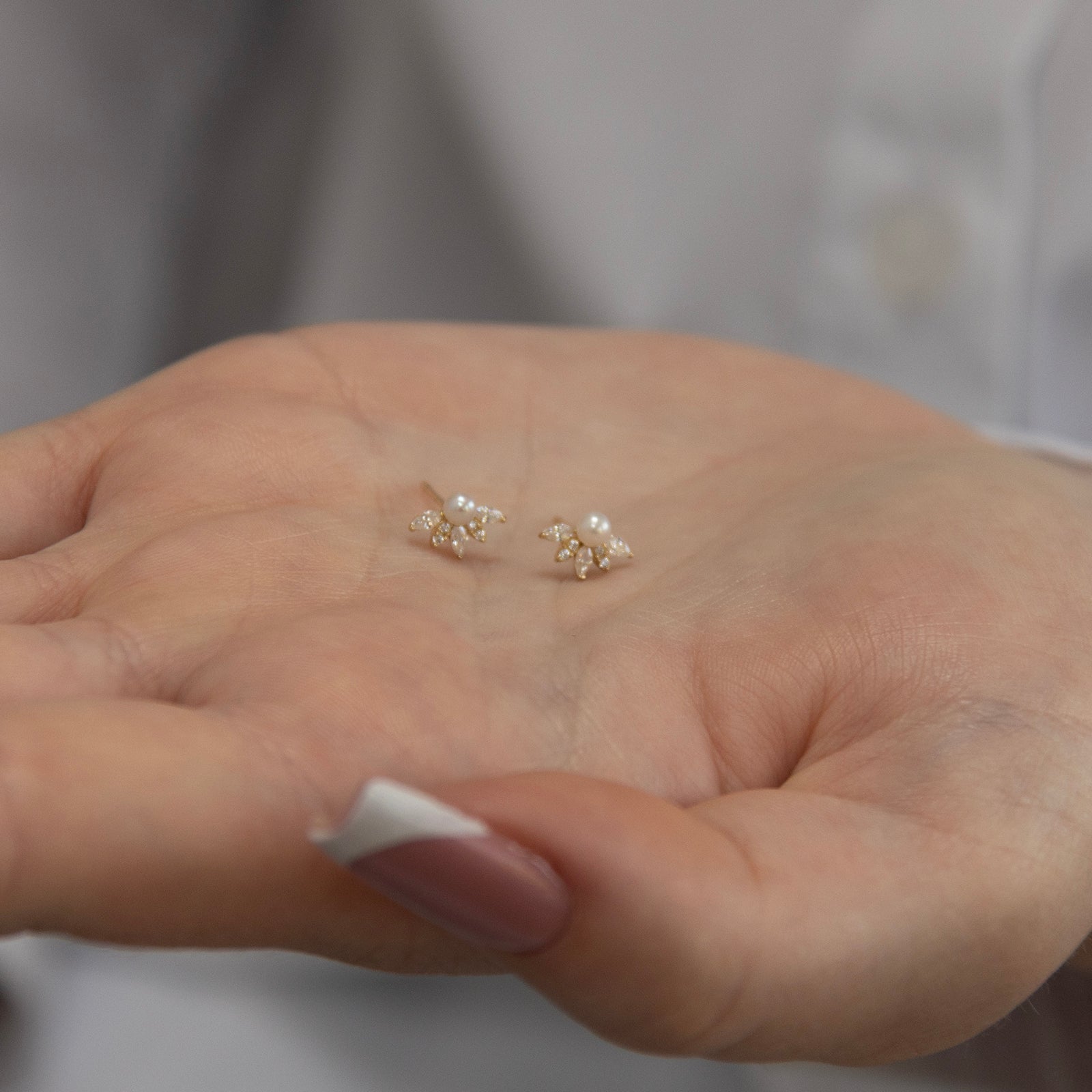 9ct gold pearl and crystal stud earrings in a hand