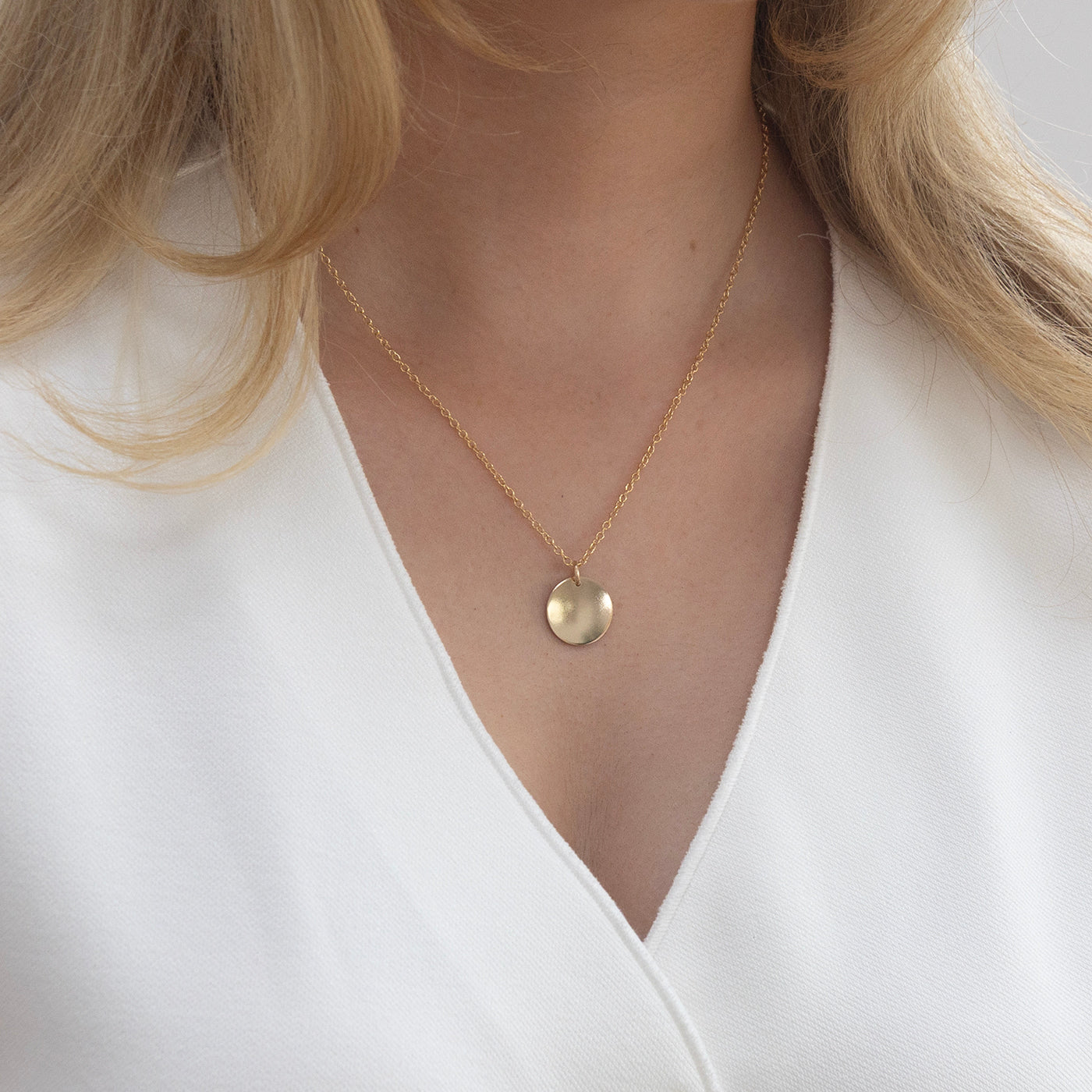 the 16 mm gold disc from lulu and belle worn on a young woman to show the size 