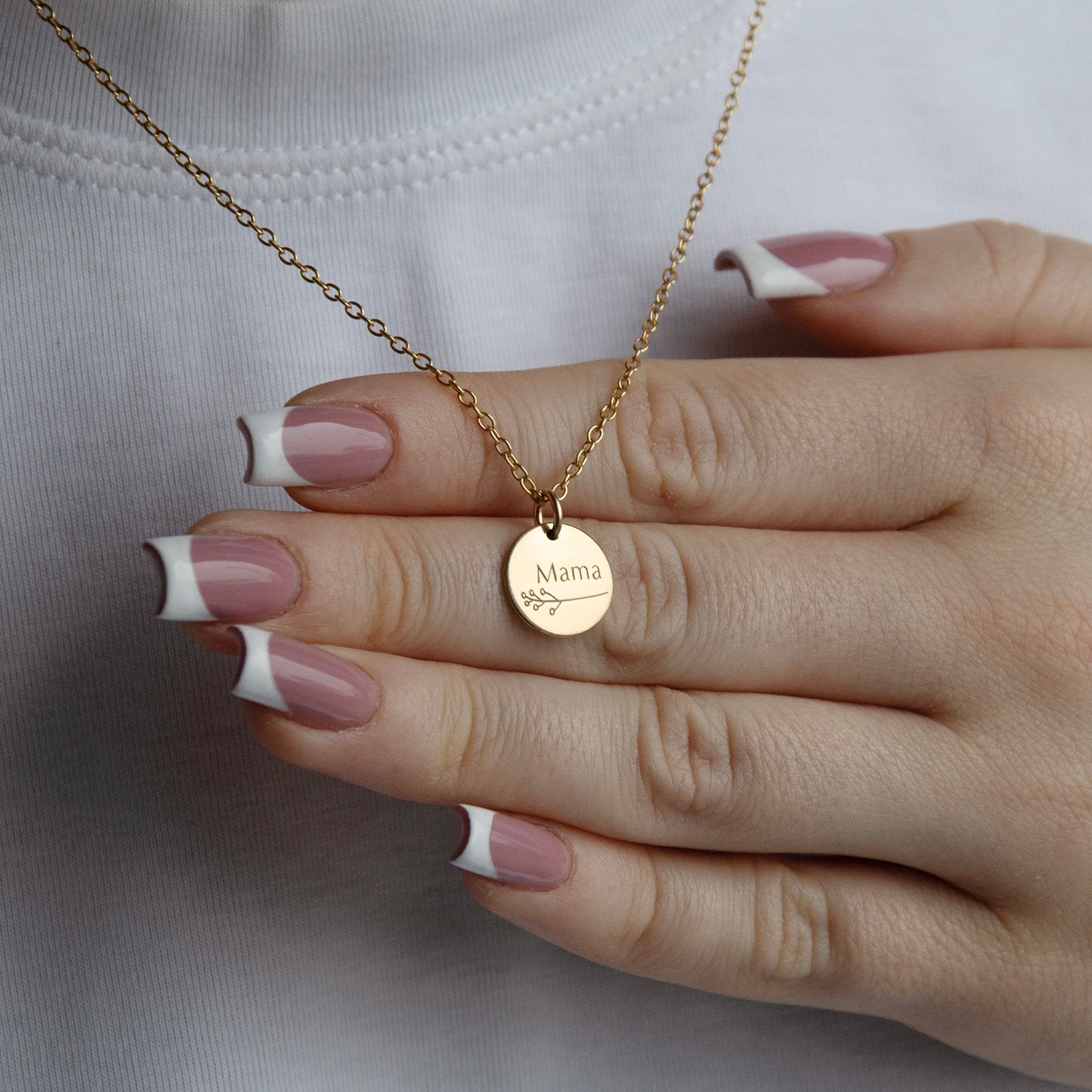 botanical mama necklace in gold in a models hand 