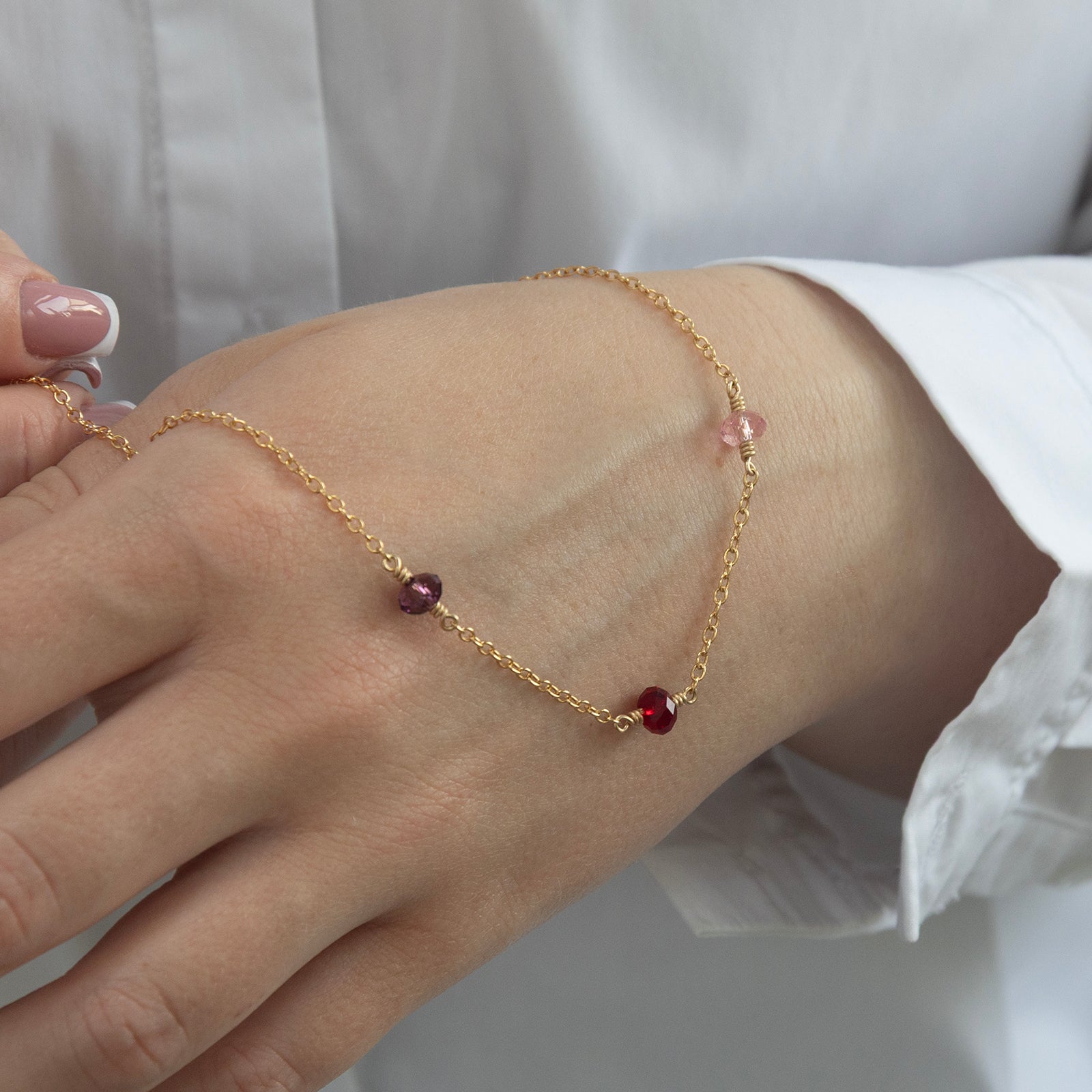 family birthstone necklace with three birthstones in a models hand 