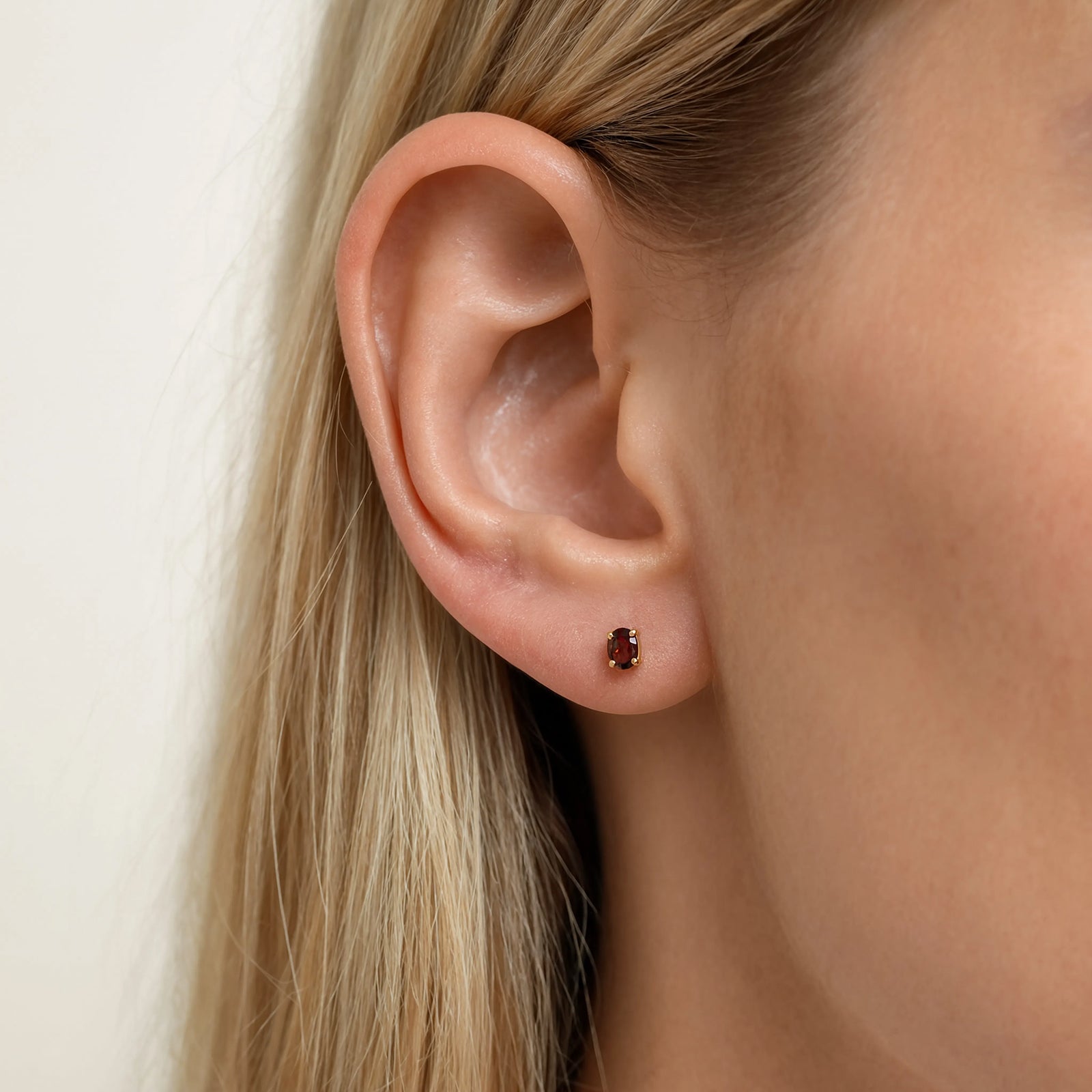 gold garnet studs in models ear - january birthstone stones worn by model 