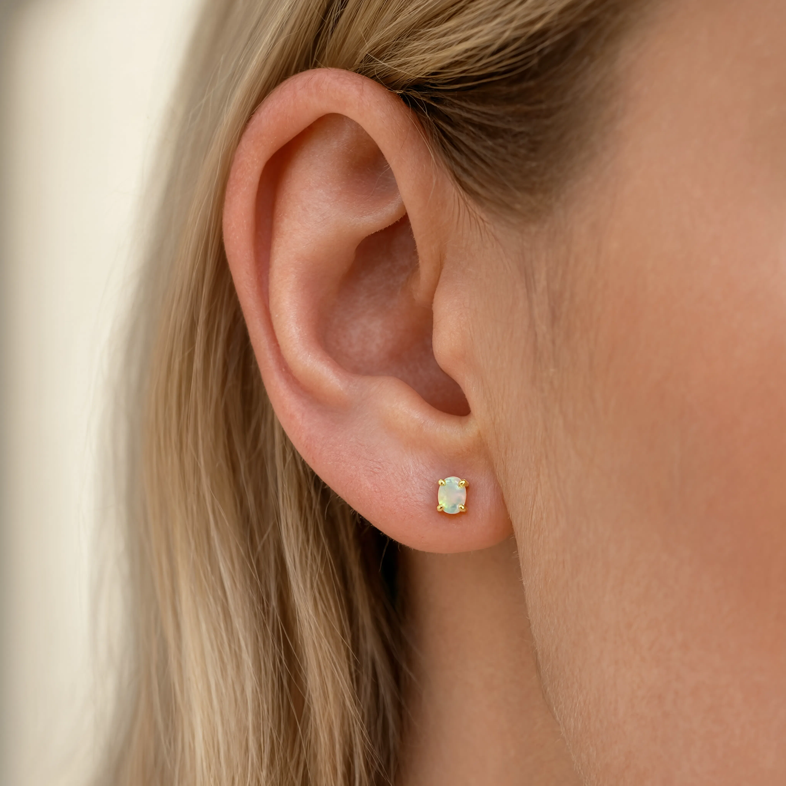 gold opal stud earring on a models ear 