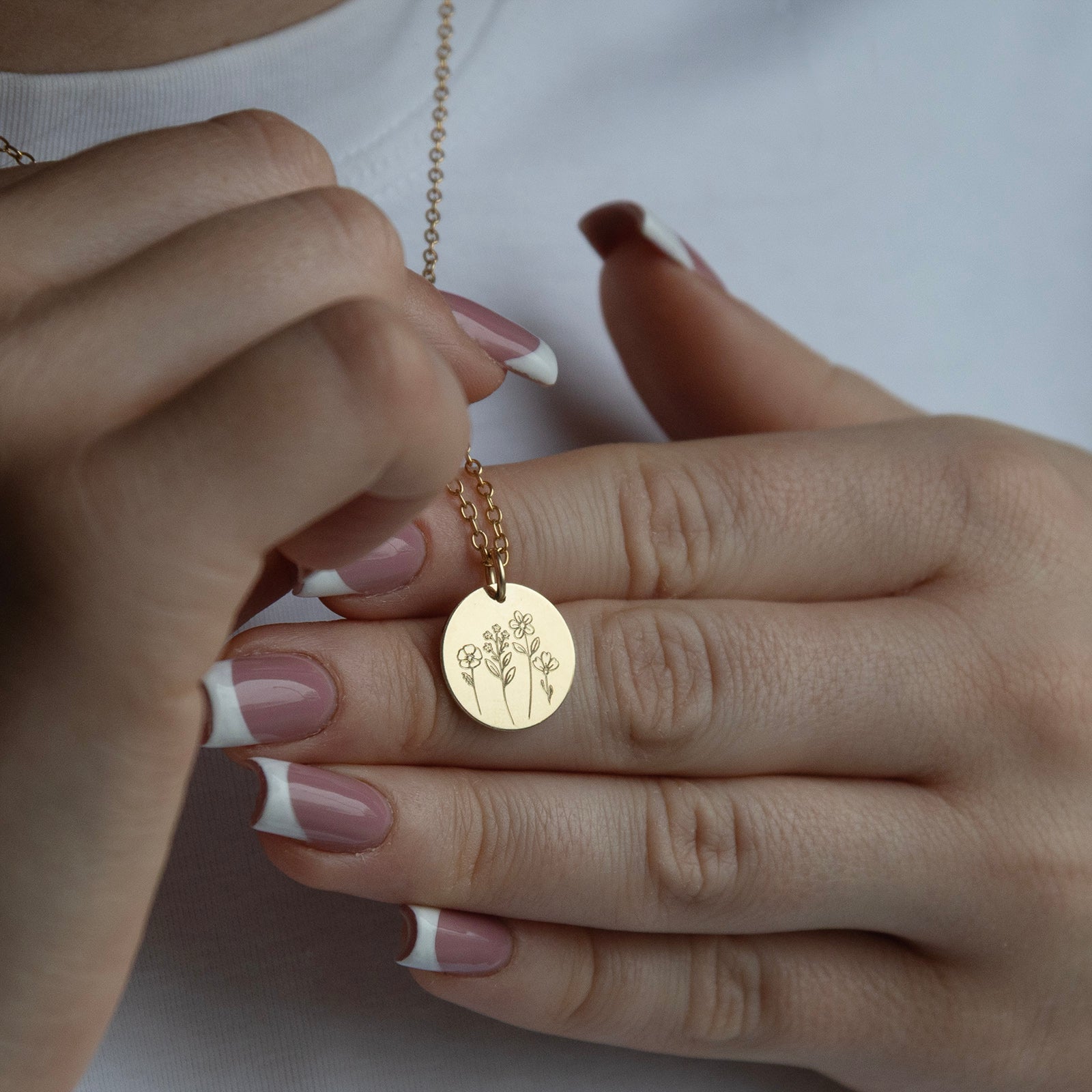 a close up of the mathair bloom necklace from the front in the hand in gold