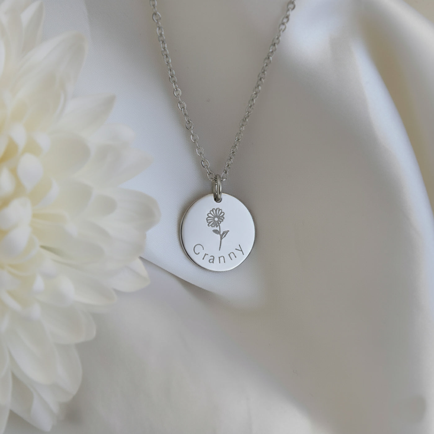 Personalised grandmother necklace in sterling silver shown from the front in a flatlay styled on soft white fabric.